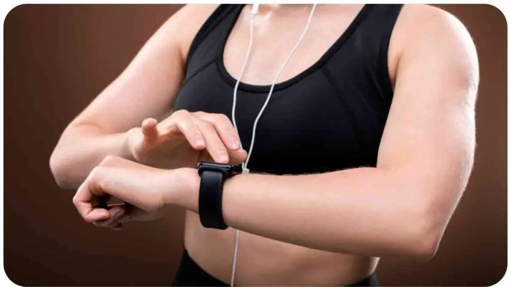 a person in a sports bra and headphones checking their smart watch.